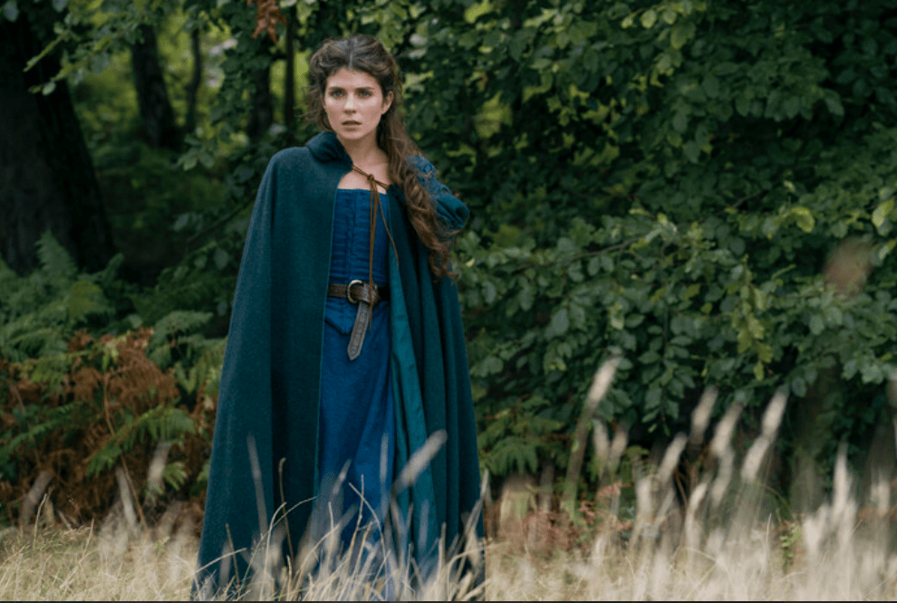 Emily Bader as Jane Grey on 'My Lady Jane' episodic photo of Jane in green cape and blue dress in woods
